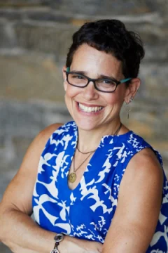 Lisa Kohn in a blue dress with her arms folded.