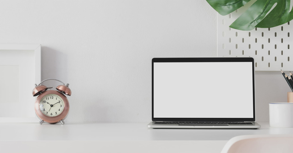 laptop on desk with alarm clock