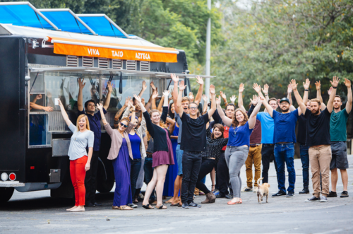 A group of people standing in front of a food truck