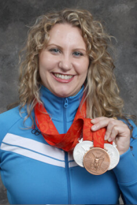 Olympian Keynote Speaker Margaret Hoelzer smiling and holding her medals.
