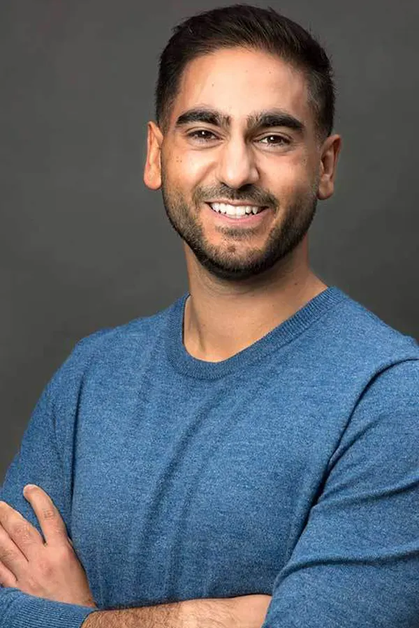 Keynote Speaker Alex Banayan in a blue shirt with his arms folded, smiling.