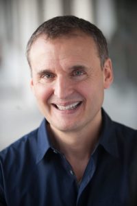 Phil Rosenthal, star of Somebody Feed Phil, smiling in a blue shirt