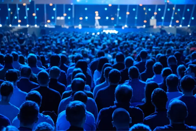 A crowd of people from behind attending a conference.