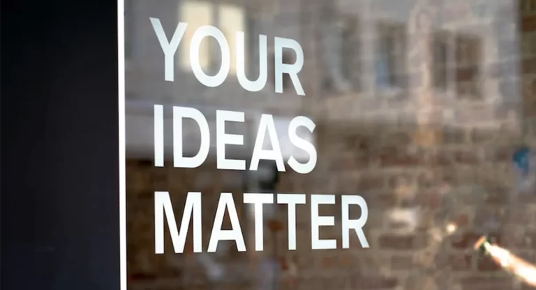A sign on glass reads motivational message, Your Ideas Matter, Write them down :)