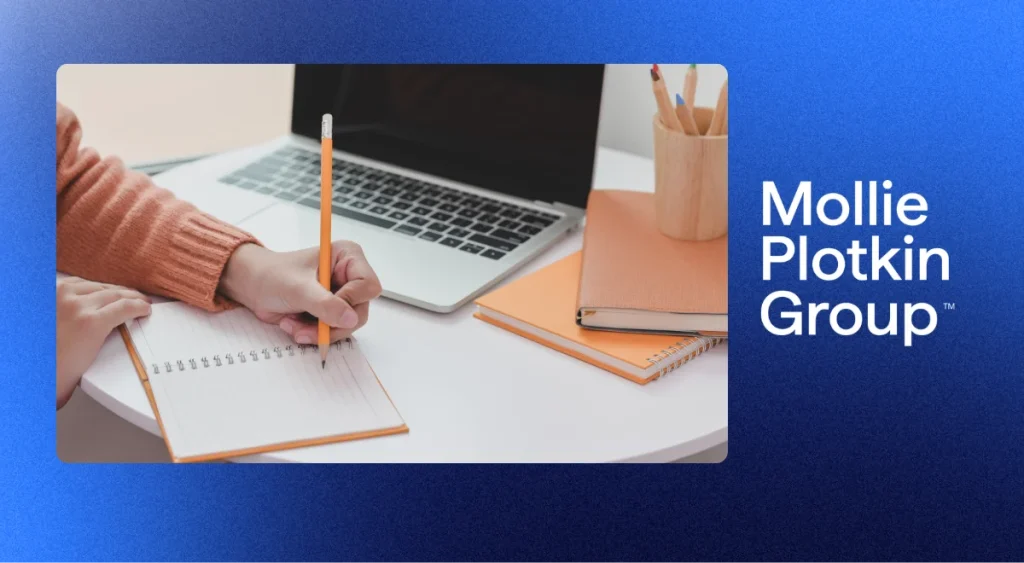 Someone writing in a notebook on a desk.